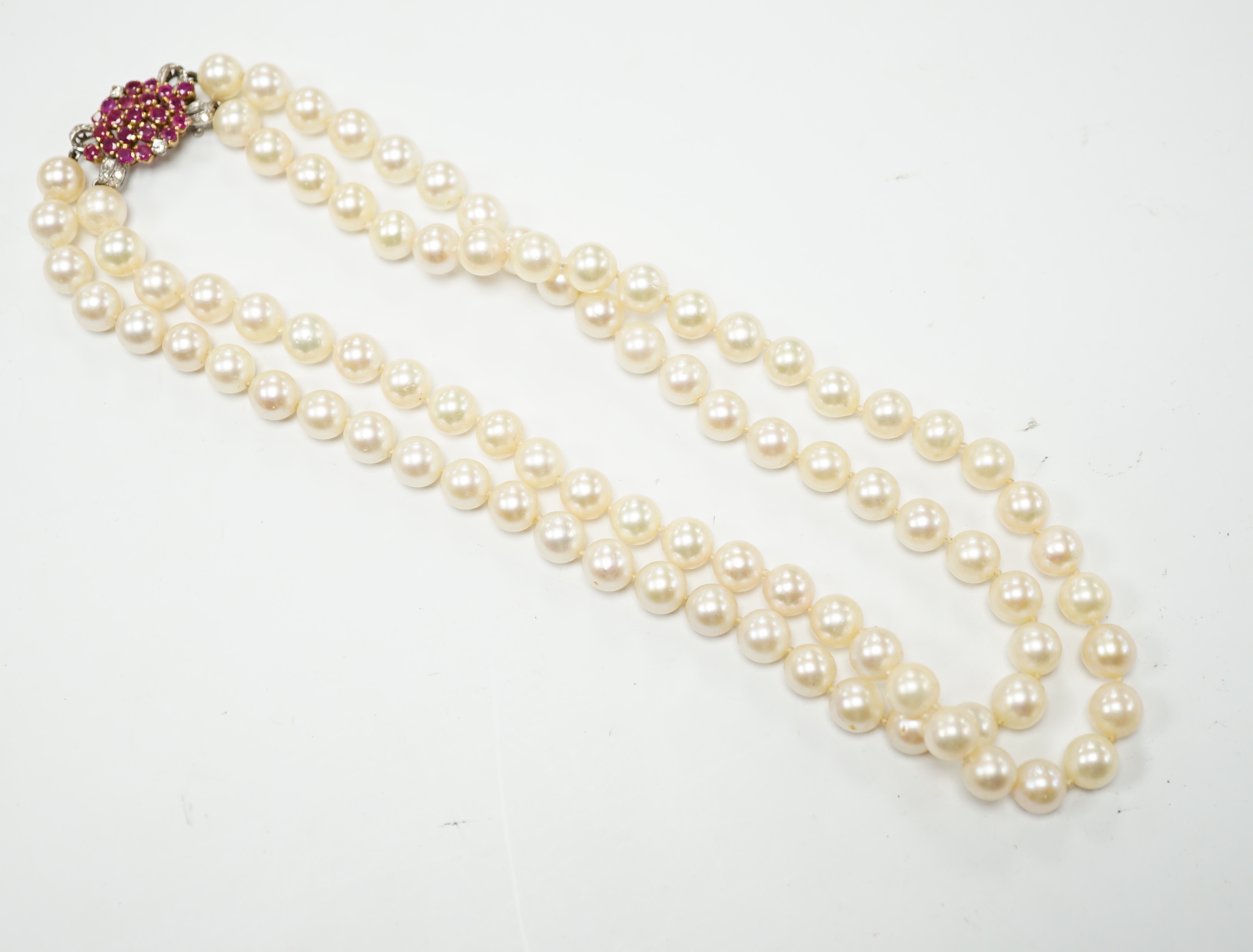 A double strand cultured pearl choker necklace with yellow and white metal, ruby and diamond cluster set clasp, 40cm.